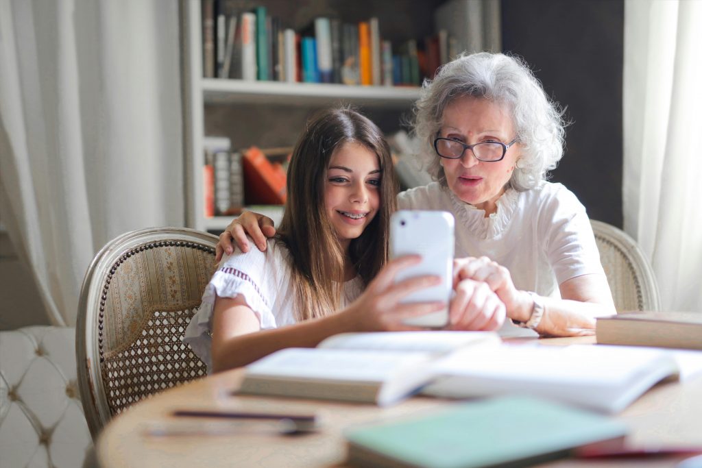 Nastolatka i starsza kobieta patrzą w kierunku smartfona rozmawiając o chorobach wieku starczego.
